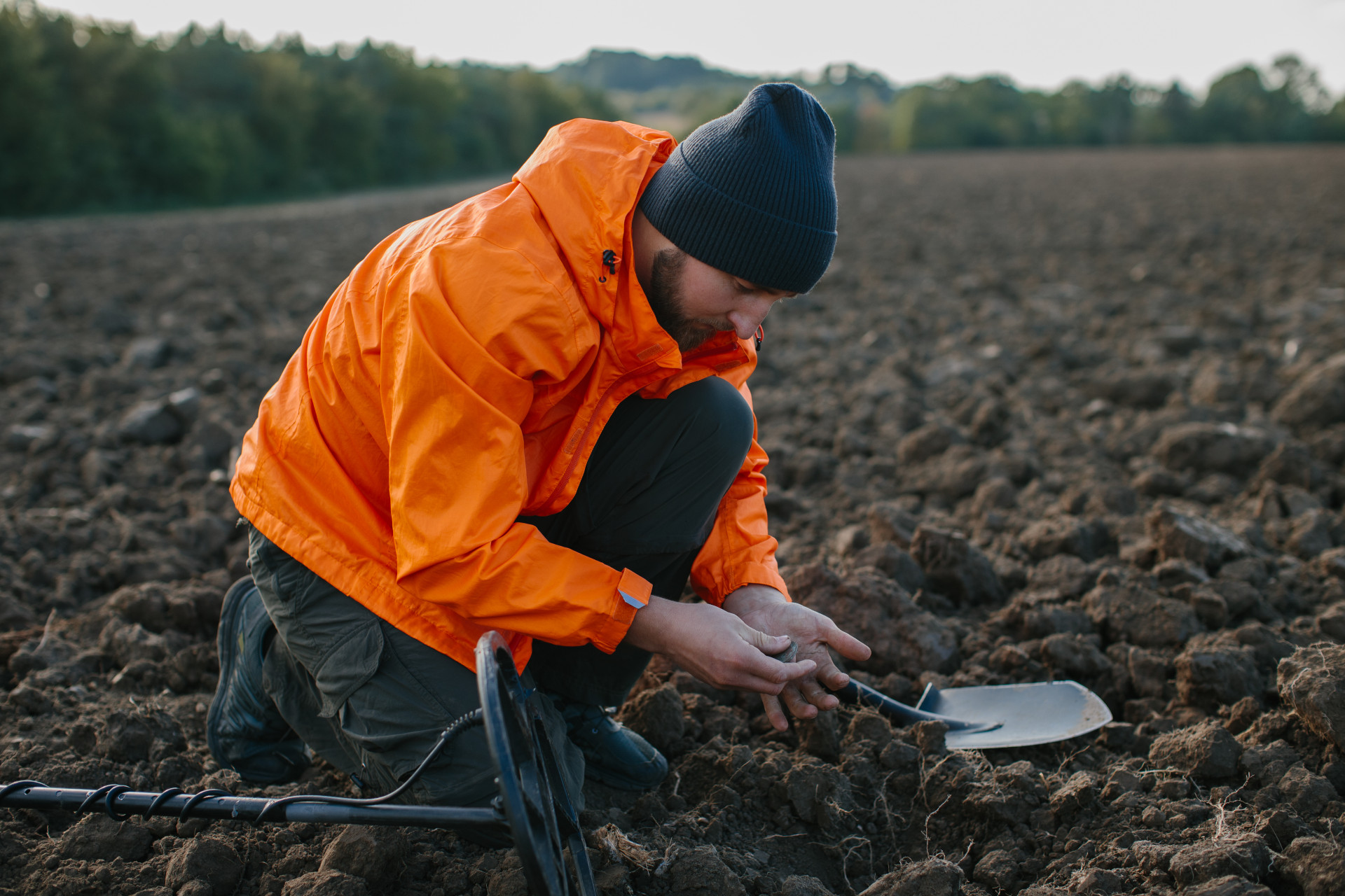 A young man is a treasure hunter. A man holds an ancient coin found with a metal detector.